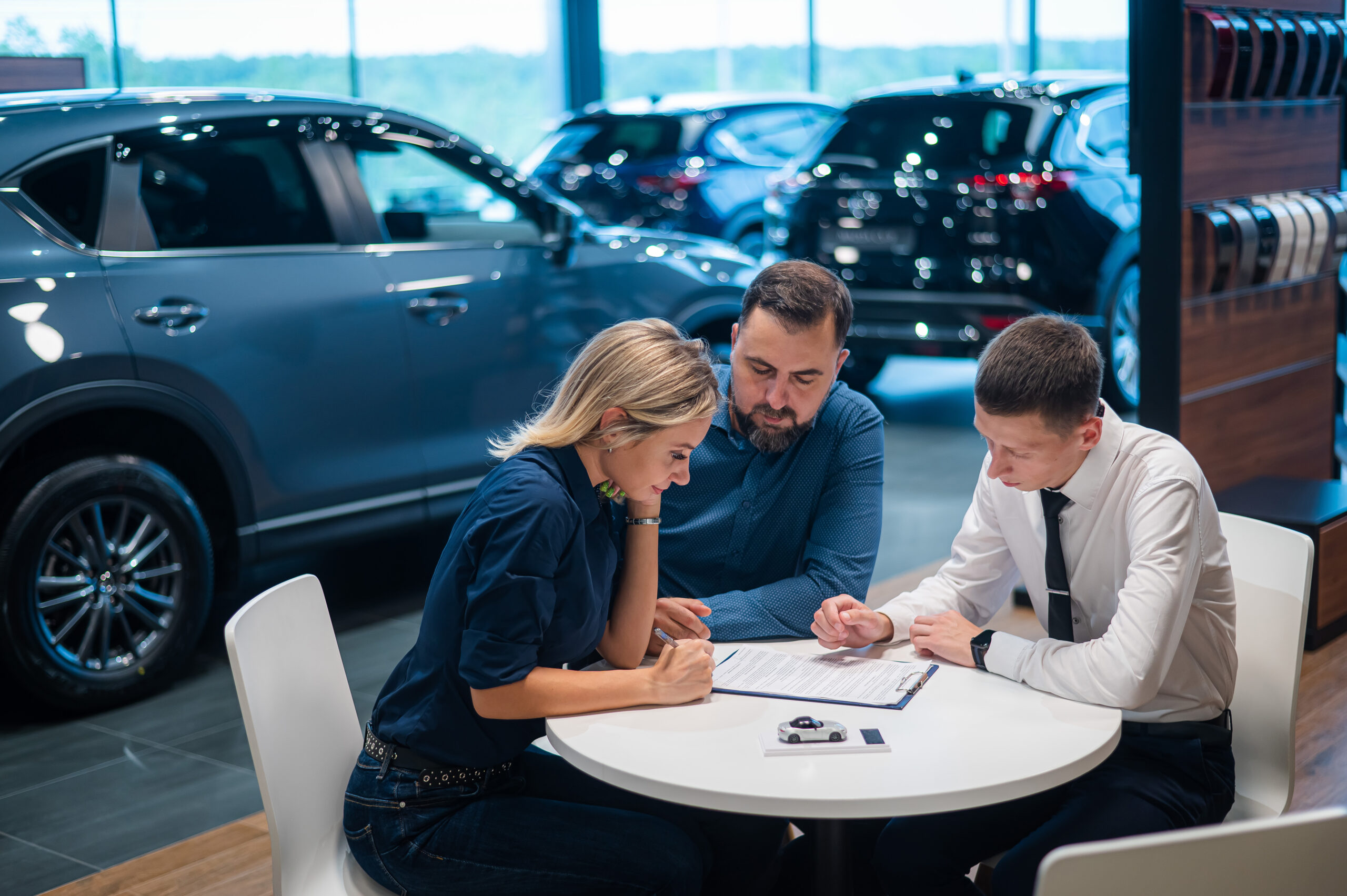Happy caucasian couple signs a contract for the purchase of a car salon